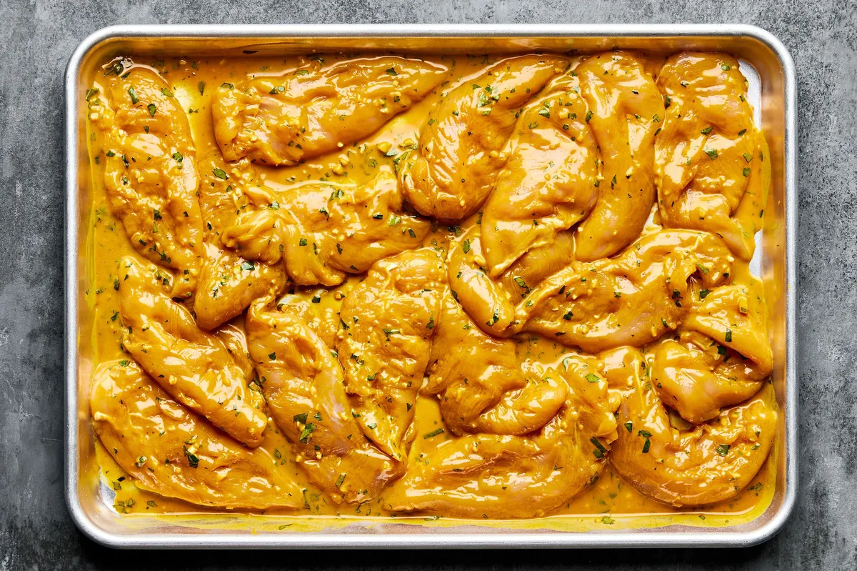 pounded raw chicken tenders covered in a coconut milk, turmeric marinade