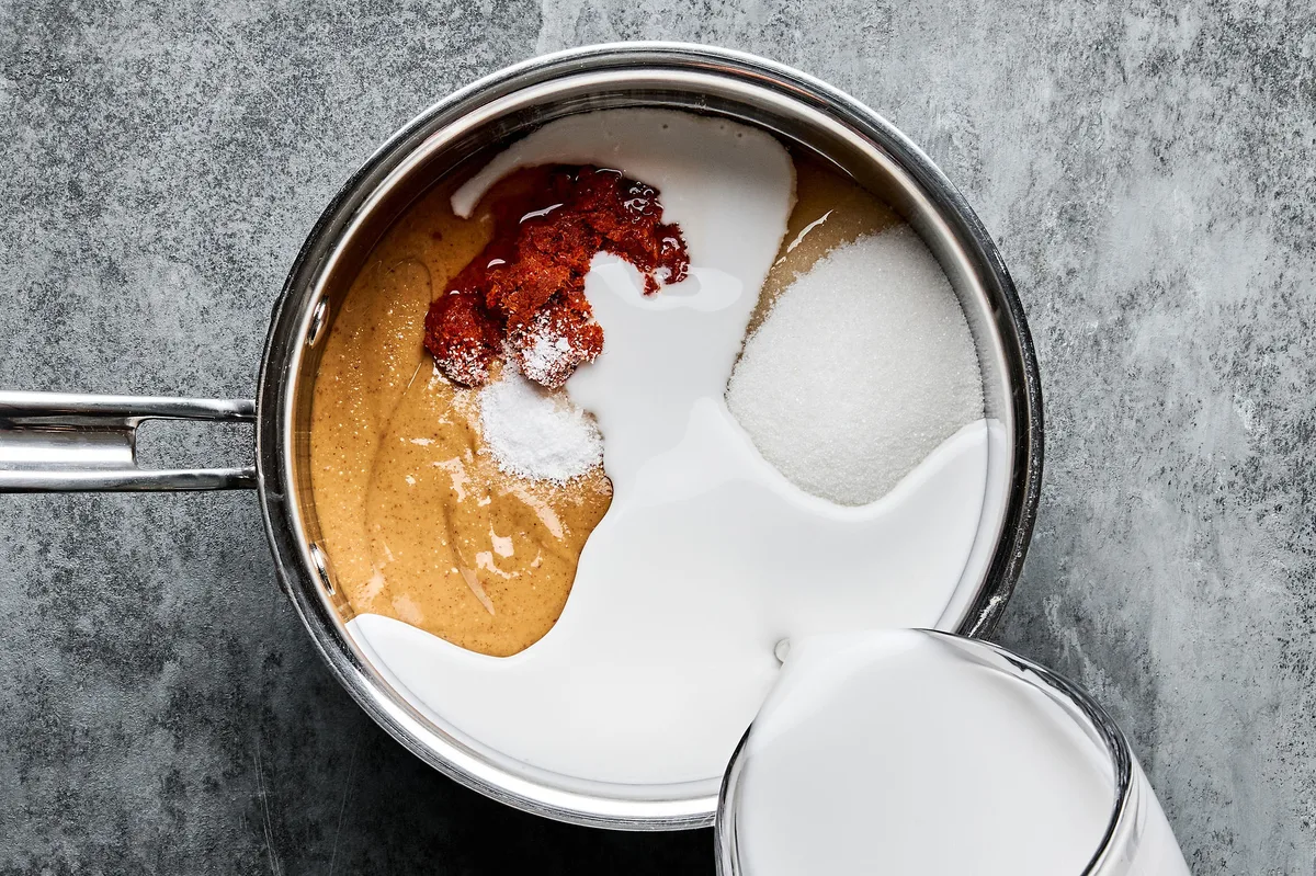 ingredients for homemade peanut sauce being added to a pot