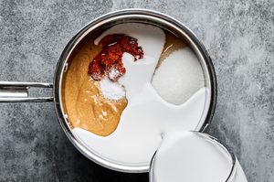 ingredients for homemade peanut sauce being added to a pot