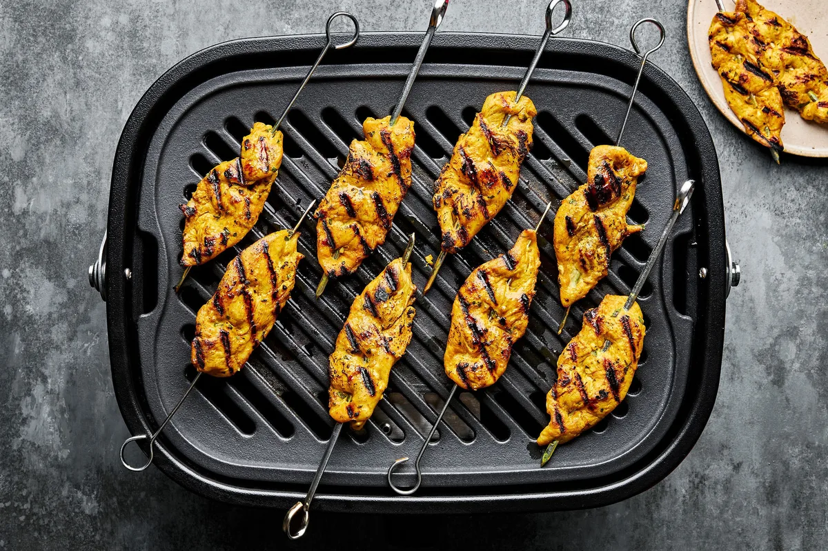 chicken satay being cooked on a grill