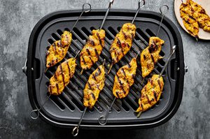chicken satay being cooked on a grill