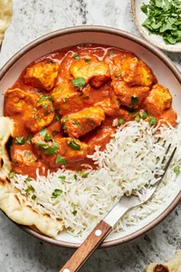 a bowl of homemade chicken tikka masala and white rice sprinkled with fresh cilantro