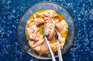 chicken being tossed with olive oil, vinegar, orange zest, orange juice, honey, Dijon, shallot, salt & pepper in a glass bowl
