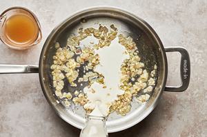 cream and stock being added to a skillet with shallots, garlic, olive oil and butter