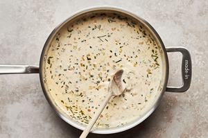 rosemary cream sauce being stirred with a wooden spoon in a sauce pan