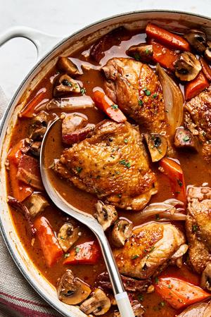 A pot of homemade coq au vin, with chicken, vegetables, and a rich red wine sauce simmering together.