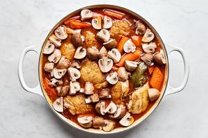 A pot of homemade coq au vin, with chicken, vegetables, and a rich red wine sauce simmering together.