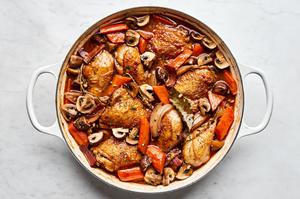 A pot of homemade coq au vin, with chicken, vegetables, and a rich red wine sauce simmering together.