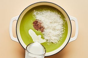 parmesan, heavy cream and nutmeg being added to a pot with blended cream of broccoli soup