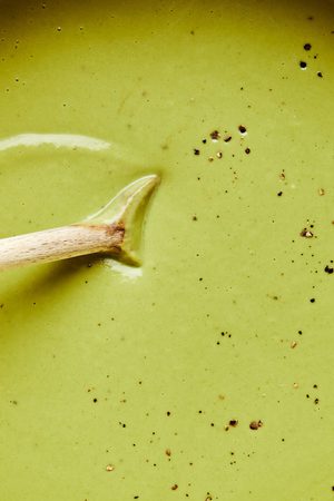 cream of broccoli soup being stirred with a wooden spoon