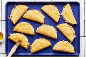 10 corn tortillas folded in half, filled with chicken, sour cream and cheese brushed with olive oil on a baking sheet
