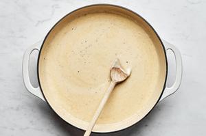 Alfredo sauce in a skillet made with butter, garlic, garlic powder, nutmeg, salt, pepper, heavy cream, Parmesan & parsley