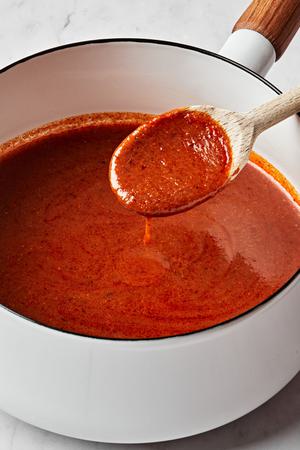 homemade enchilada sauce in a pot spiced with chili powder, garlic powder, onion powder, cumin, oregano, and tomato paste