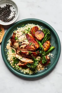 Honey harissa chicken, potatoes and broccoli served over couscous and drizzled with tahini sauce