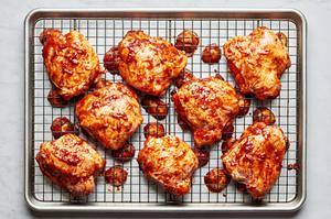 chicken tossed with harissa, olive oil, salt, garlic powder, and onion powder on a cooling rack on top of a baking sheet