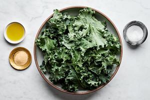 Kale, olive oil, salt and seasonings in separate prep bowl to make homemade crispy kale chips.