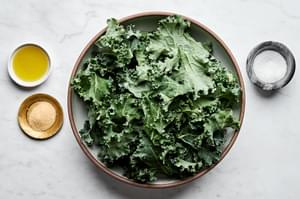 Kale, olive oil, salt and seasonings in separate prep bowl to make homemade crispy kale chips.