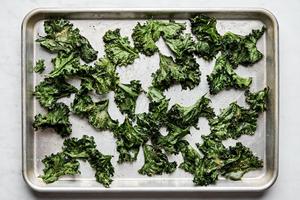 Crispy homemade kale chips, lightly seasoned and baked to golden perfection on a baking sheet.