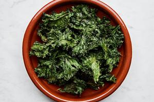 Crispy homemade kale chips, lightly seasoned and baked to golden perfection, arranged in a bowl for serving.