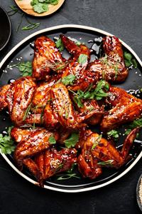 Korean Style Baked chicken wings sprinkled with cilantro, green onions and sesame seeds on a serving platter