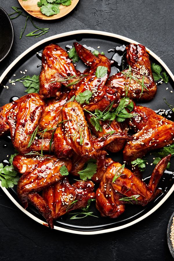 Korean Style Baked chicken wings sprinkled with cilantro, green onions and sesame seeds on a serving platter