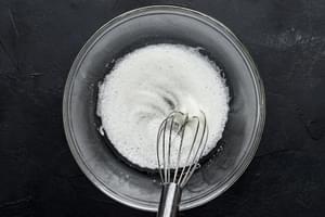 egg whites being whisked in a bowl until frothy