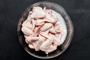 chicken wings that have been patted dry and seasoned with salt being tossed in whisked egg whites