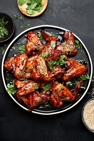 Korean Style Baked chicken wings sprinkled with cilantro, green onions and sesame seeds on a serving platter
