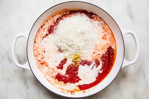 heavy cream, parmesan, lemon juice & zest being added to a pot with tomatoes, calabrian chilis, salt, olive oil and garlic