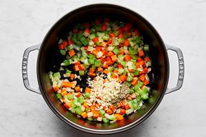 onions, celery, carrots, garlic and fennel seeds being cooked in olive oil in a large soup pot