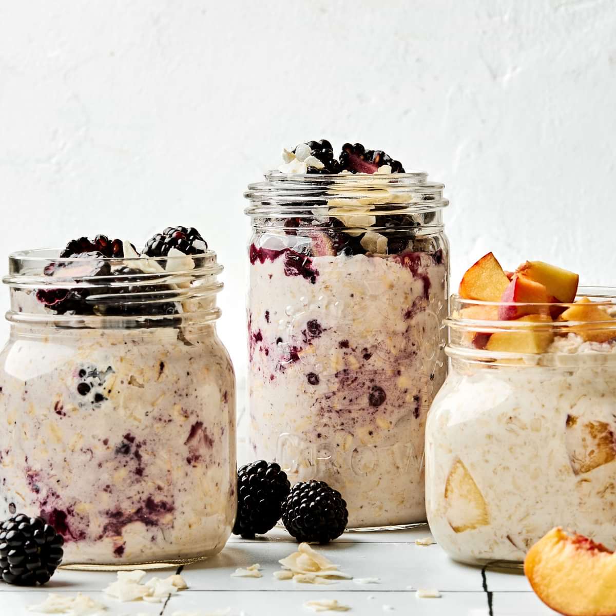 Three jars of overnight oats with various toppings: fruit, chia seeds, jam and coconut