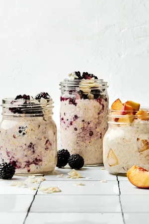 Three jars of overnight oats with various toppings: fruit, chia seeds, jam and coconut