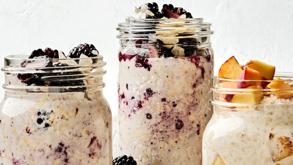 Three jars of overnight oats with various toppings: fruit, chia seeds, jam and coconut