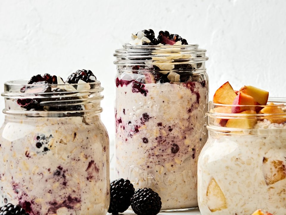 Three jars of overnight oats with various toppings: fruit, chia seeds, jam and coconut