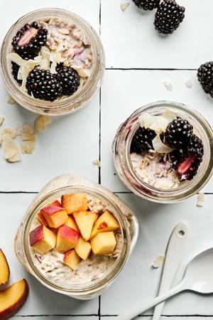 Three jars of overnight oats with various toppings: fruit, chia seeds, jam and coconut