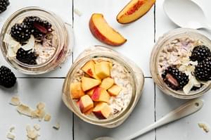 3 jars of overnight oat, two with blackberries and one with peaches.