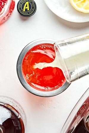 bourbon, amaro, Aperol, and lemon juice being combined in a cocktail shaker