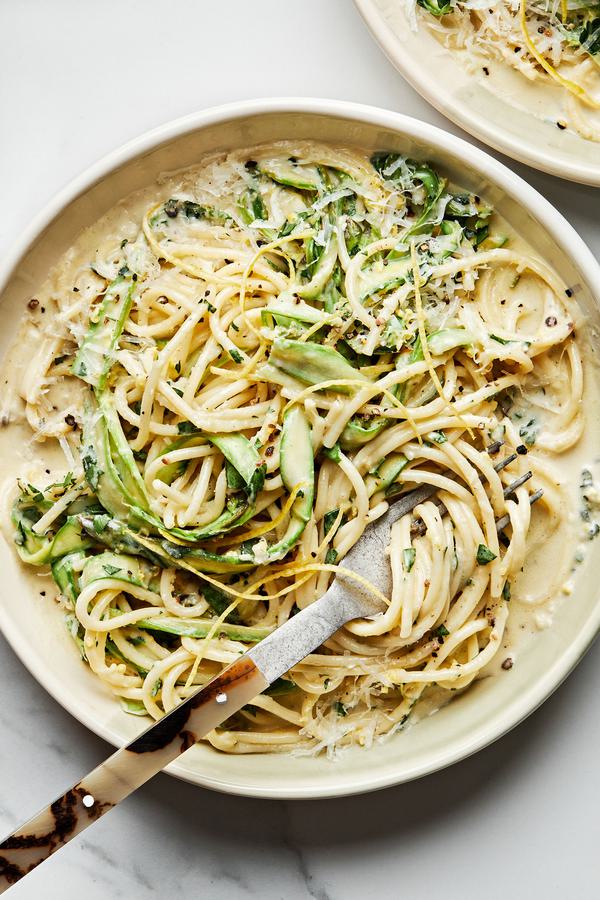 Pasta al Limone with Asparagus topped with pecorino Romano, lemon zest, and pepper in a pasta bowl with a fork