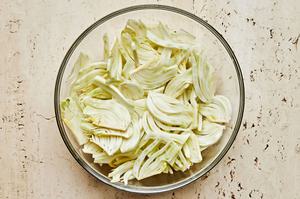 sliced fennel bulbs tossed with olive oil and salt in a large glass bowl