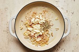 shallots, garlic and fennel seeds being cooked in a pan with olive oil