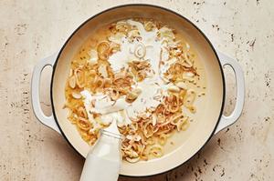 white wine and cream being added to a pan with cooked shallots, garlic and fennel seeds