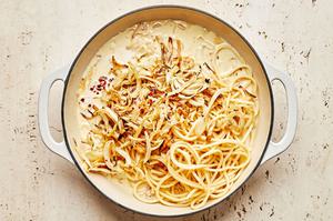 pasta noodles, roasted fennel and lemon juice being tossed with creamy pasta sauce in a skillet