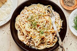 a bowl of creamy pasta with roasted fennel topped with fresh parmesan and red pepper flakes on a plate