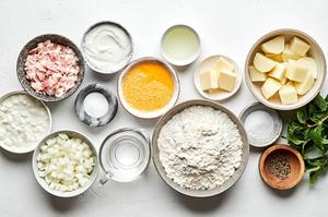 flour, egg, butter, potatoes, bacon, onion, spices, cottage cheese and sour cream in in prep bowls for pierogi