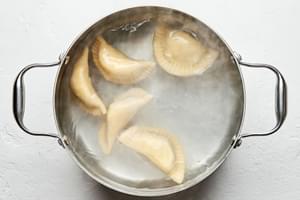 pierogis being boiled in a large pot of water
