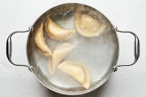 pierogis being boiled in a large pot of water