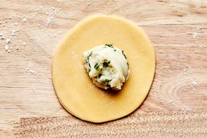a circle of pierogi dough with mashed potato filling on top