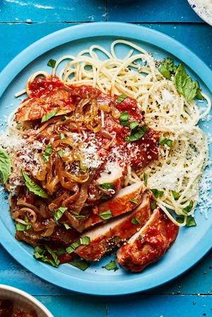 pork chops braised in tomato sauce served on cooked pasta noodles and topped with caramelized onions, basil and parmesan
