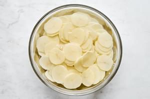 Thinly sliced potatoes being soaked in cold water to use to make potatoes au gratin.