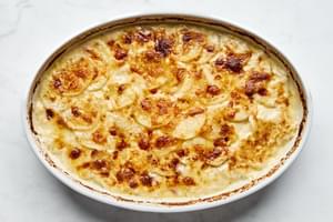 A casserole dish filled with golden, creamy homemade potatoes au gratin, topped with a crispy cheese layer.
